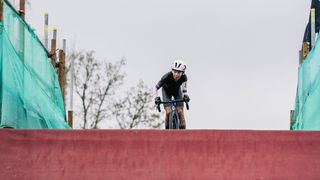 Cyclocross rider cresting over a man made climb