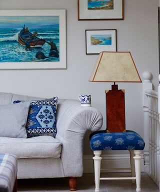A table lamp showing small living room lighting ideas beside a pale sofa with blue accessories.