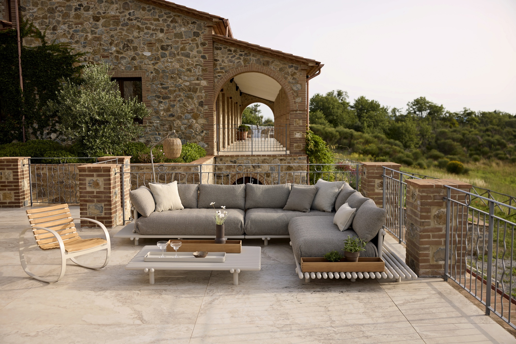 a gray outdoor sofa on a large patio in front of a large stone house