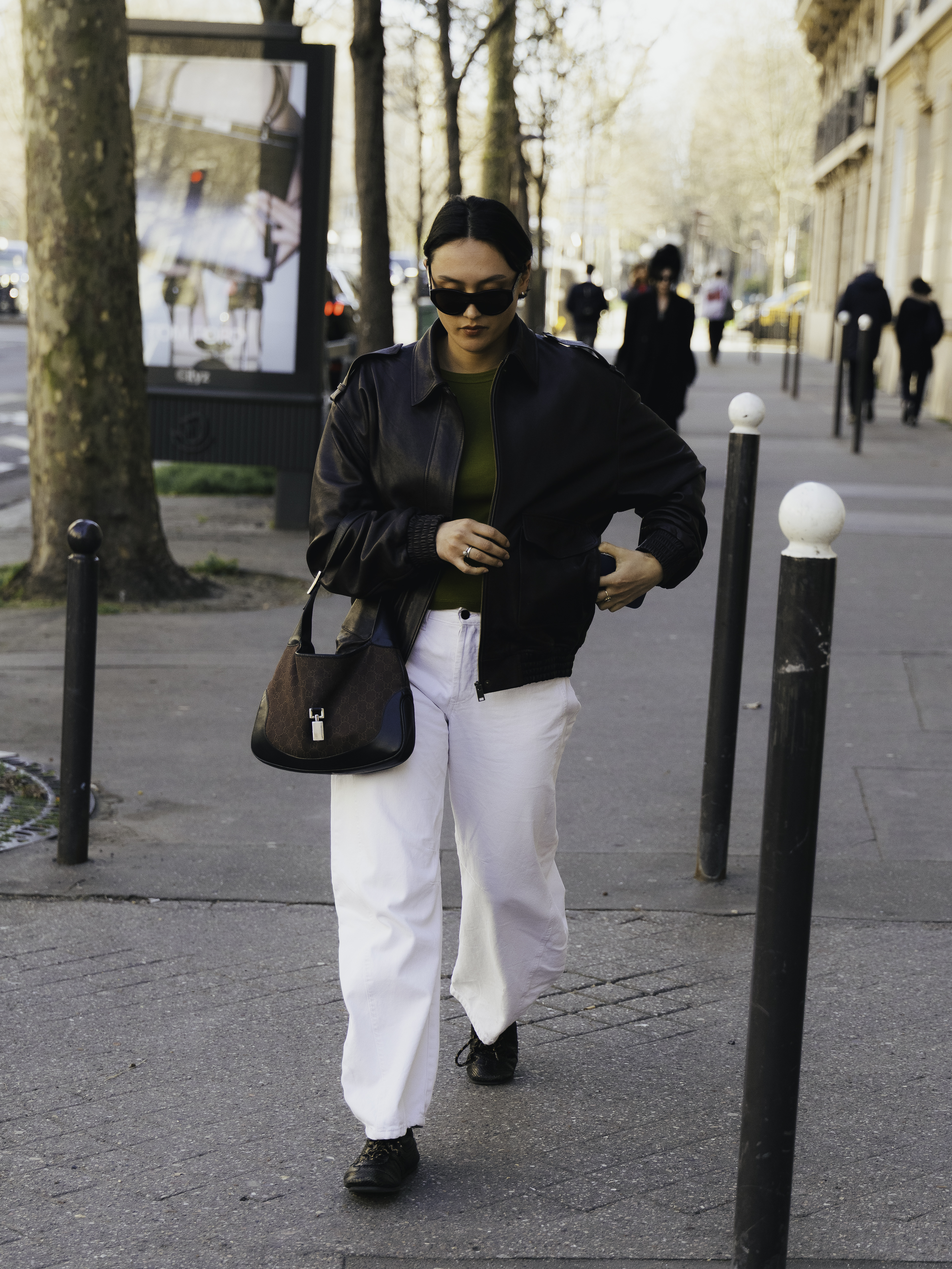 woman wearing leather jacket, white pants, and loafers