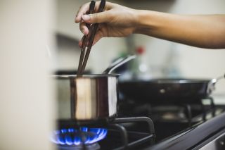 Woman stirring saucepan on a gas hob as prices rise across the UK