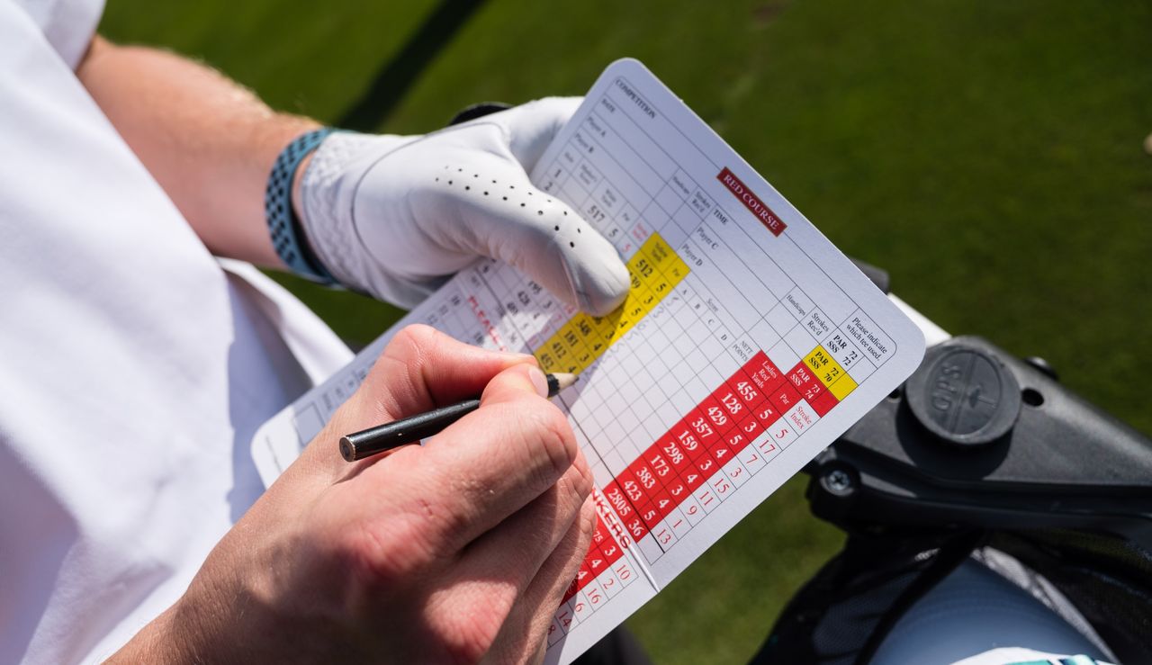 What is Stableford in Golf? Player marking a golf scorecard with a pencil