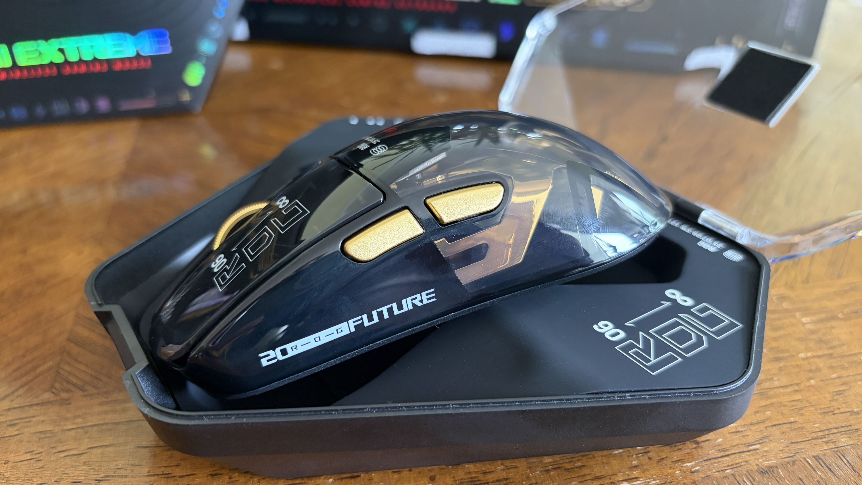 Black ASUS ROG gaming mouse with gold buttons and DPI markings on a table.