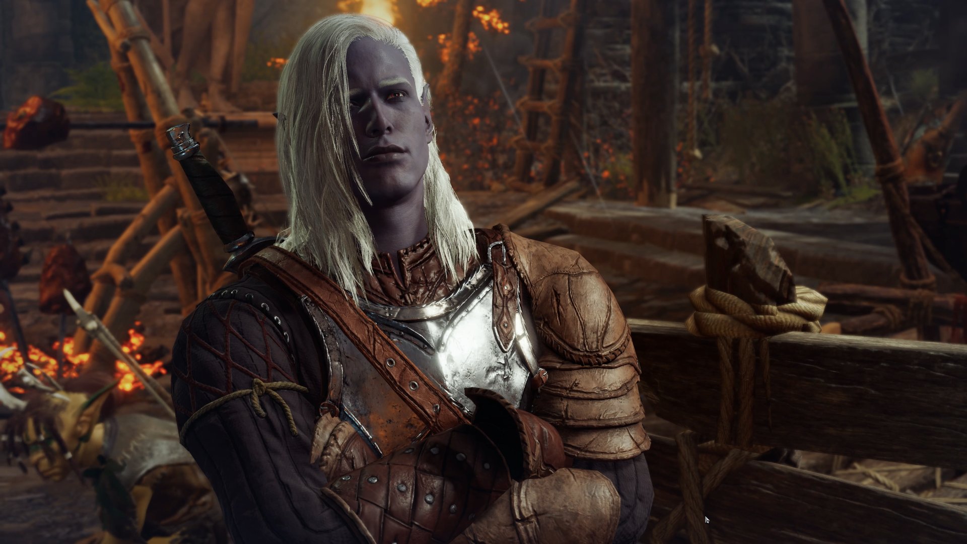 The dark elf is looking at the camera and wearing armor and crossing his arms