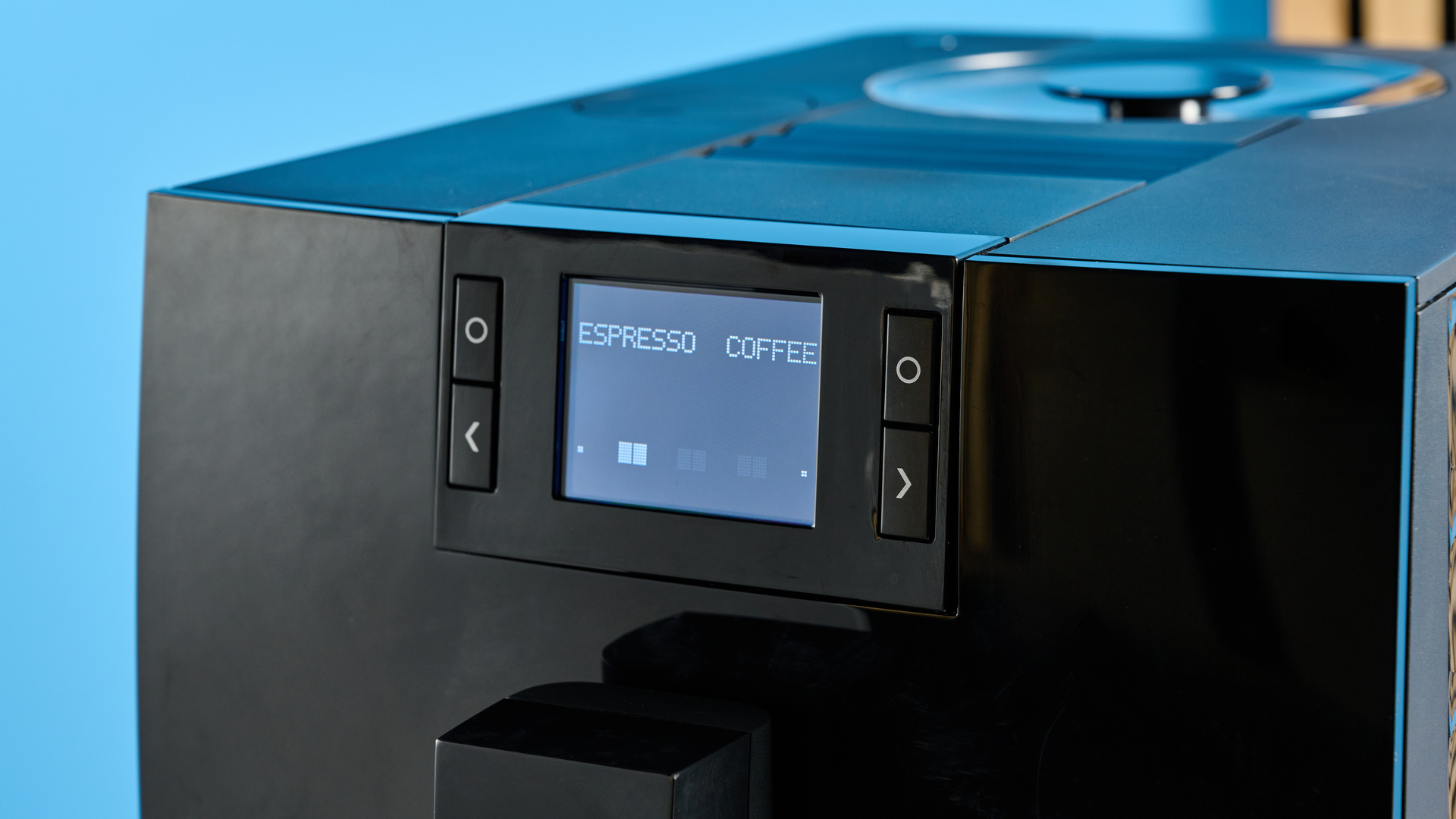 the jura c8 automatic coffee machine in piano black photographed with a blue and wood background