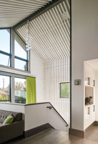 Linear pattern on ceiling, with grey couch and staircase at Alameda Renovation