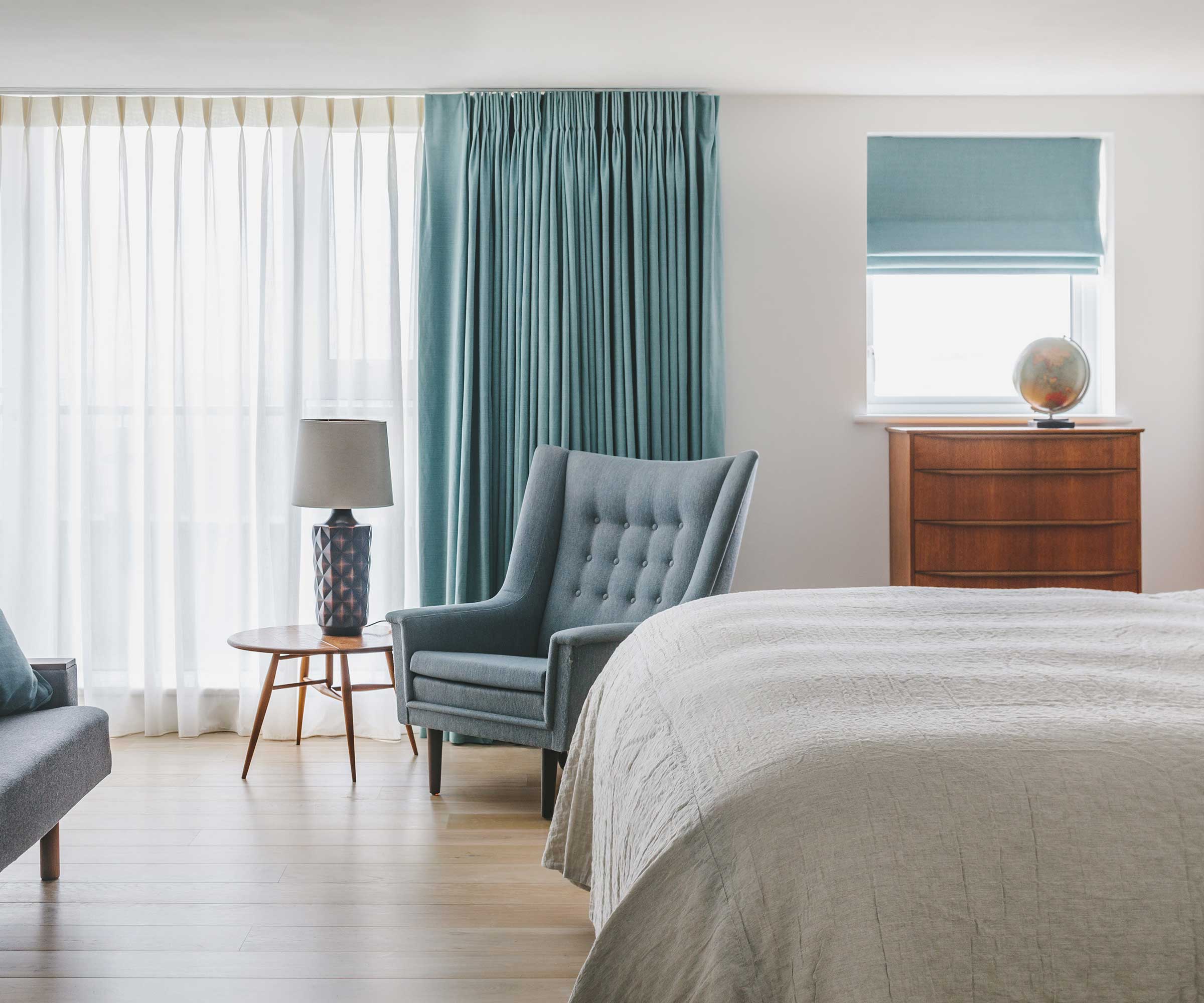 bedroom with wooden flooring and full length blue curtains