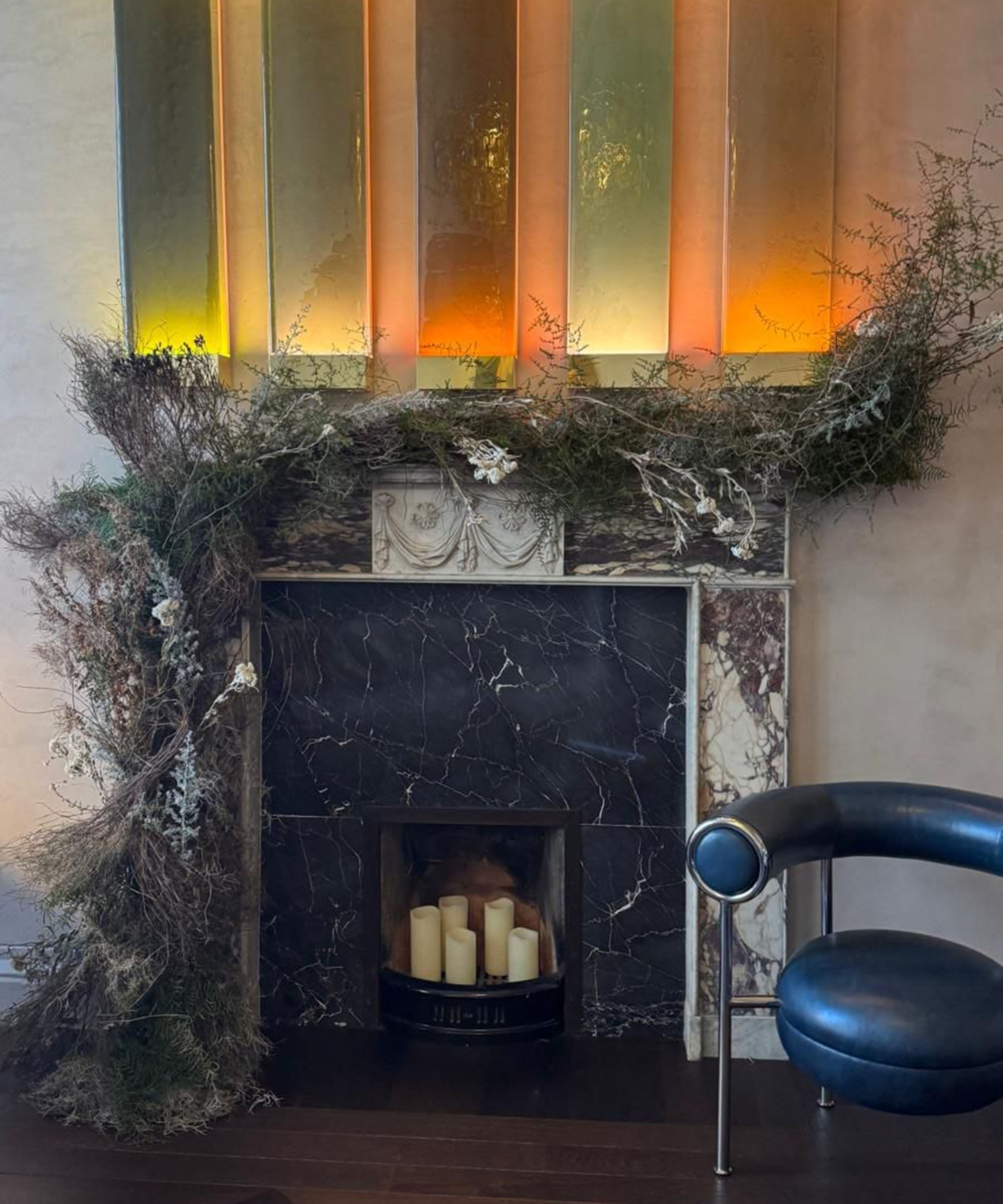 Fireplace decorated for Christmas with sculptural foliage and pillar candles