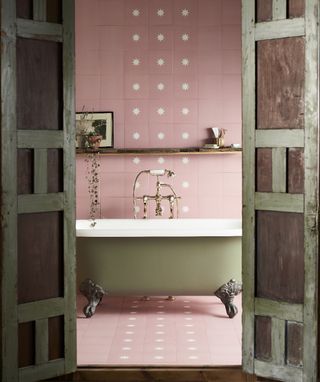 A bathroom with a freestanding bath and pink star motif bathroom tiles