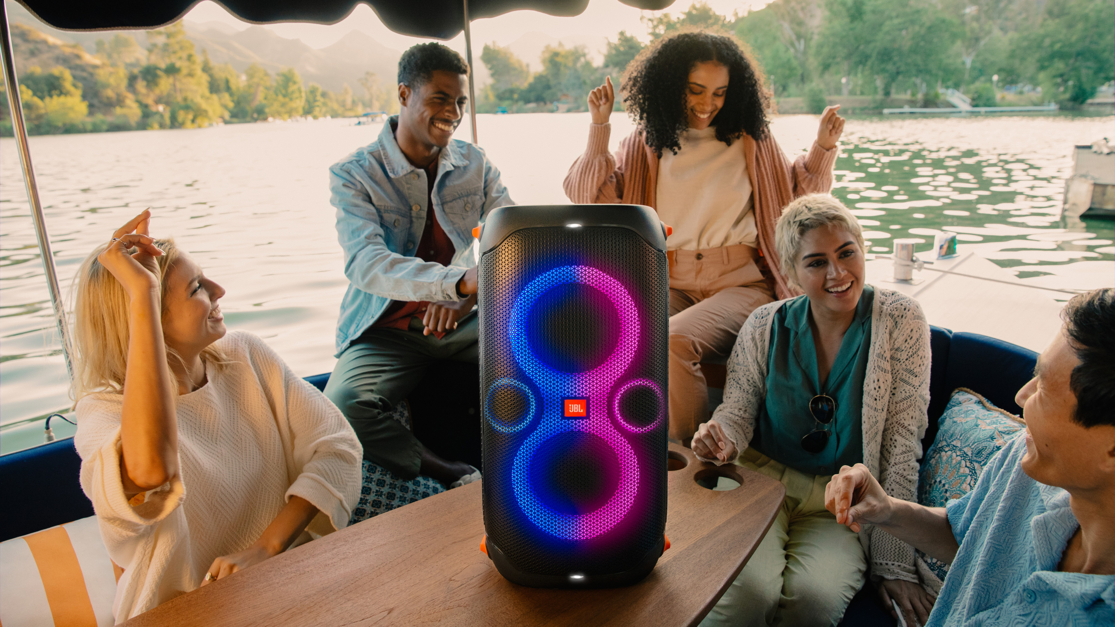 The JBL PartyBox 110 on a boat surrounded by people.