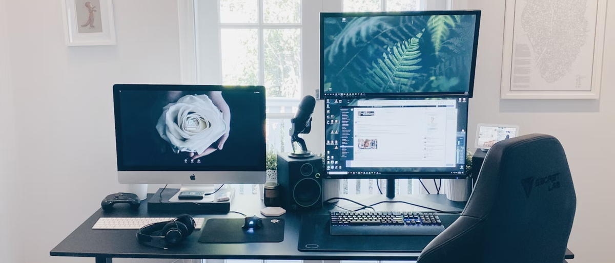 A home office with a chair, laptop, monitor, and microphone