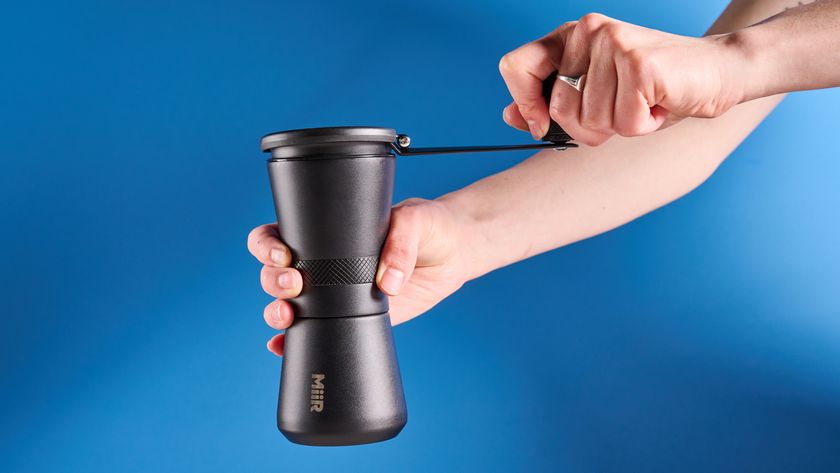 MiiR New Standard Hand Grinder in matte black photographed in front of a blue background