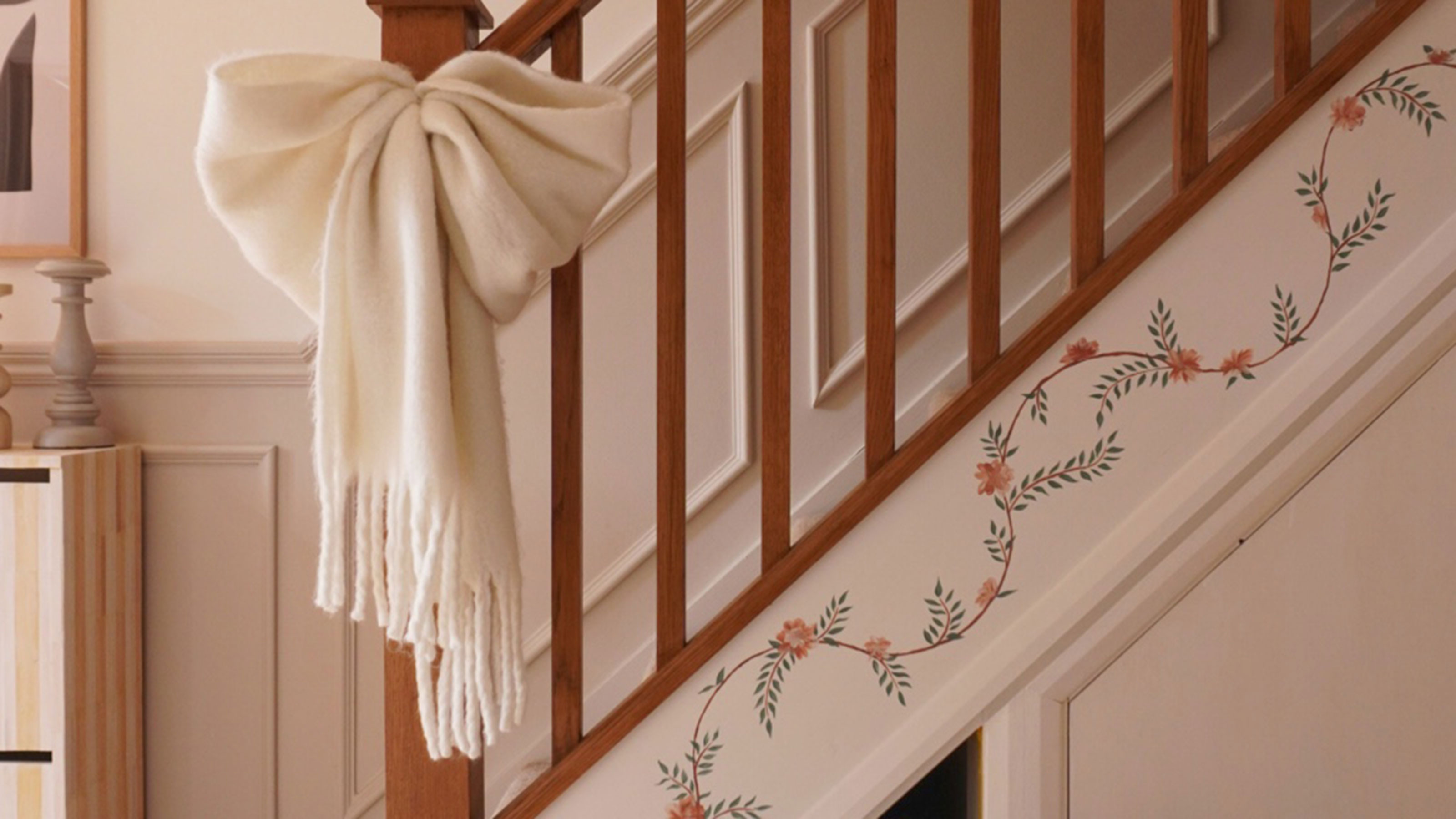 Staircase with floral mural painted up the sideboard and fabric white bow tied around banister pole