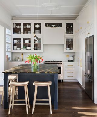 Small white kitchen ideas with a dark blue island, and white full height cupboards with glass panels