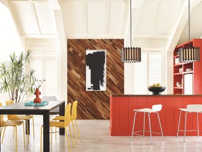 A bright modern kitchen with red cabinets and a black dining table with yellow metal chairs