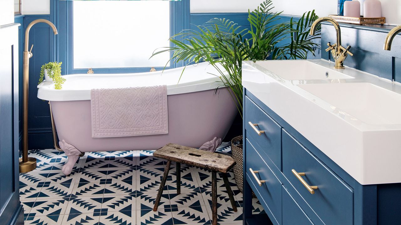 Small bathroom with small painted roll top bath and patterned tiles on floor