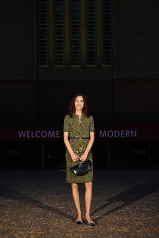 Alexa Chung wearing a green belted dress with a black bag at the Gucci Cruise 2025 show.
