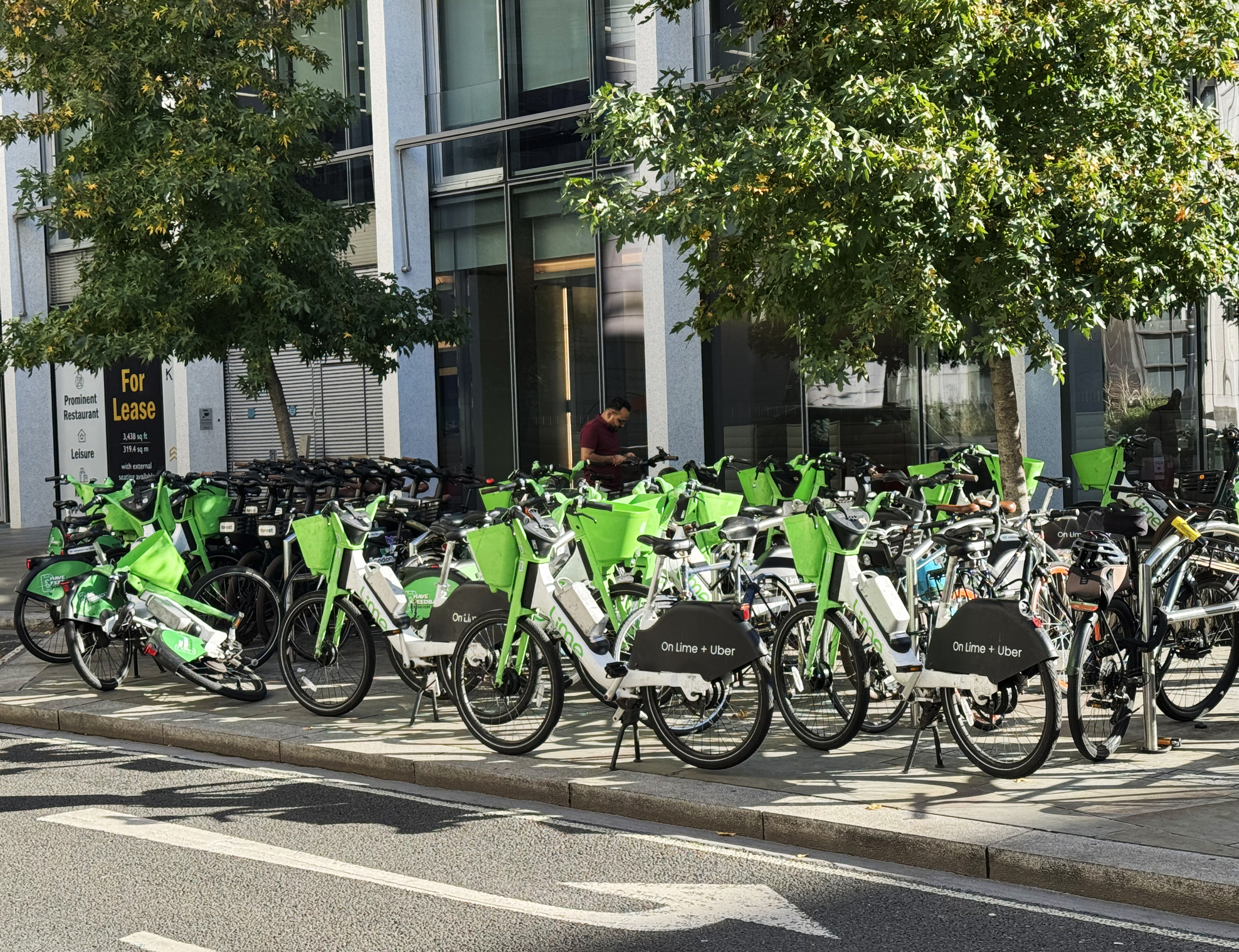Lime E-bikes lined up on the side of a street in London.