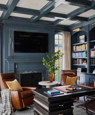 home office room with dark blue-gray walls and built-in shelving, ceiling beams and cozy decor