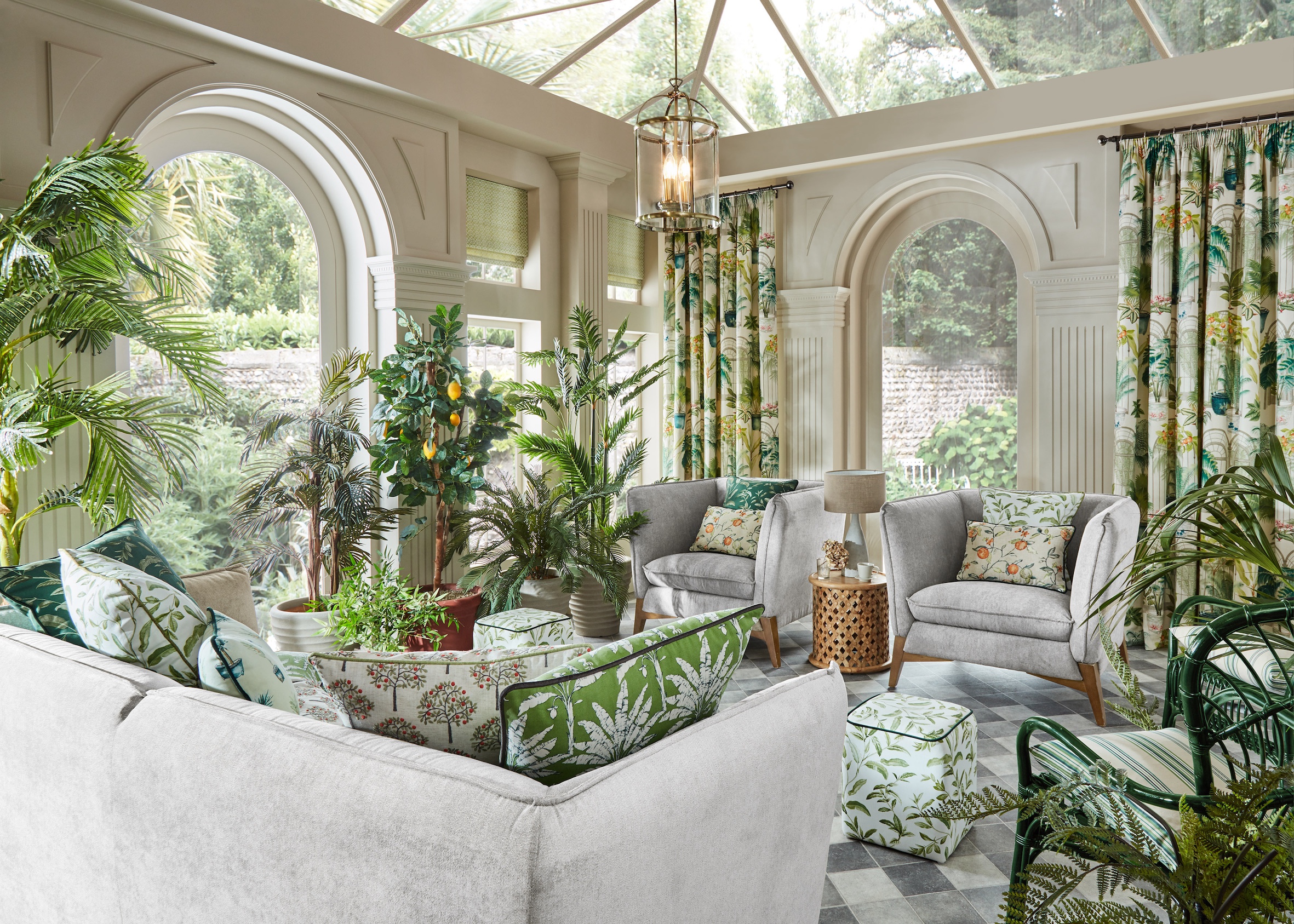 conservatory with patterned green and white curtains, plain green blinds and pale sofas with lots of scatter cushions