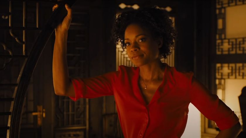 Naomie Harris stands in a doorway in a red dress in Skyfall.