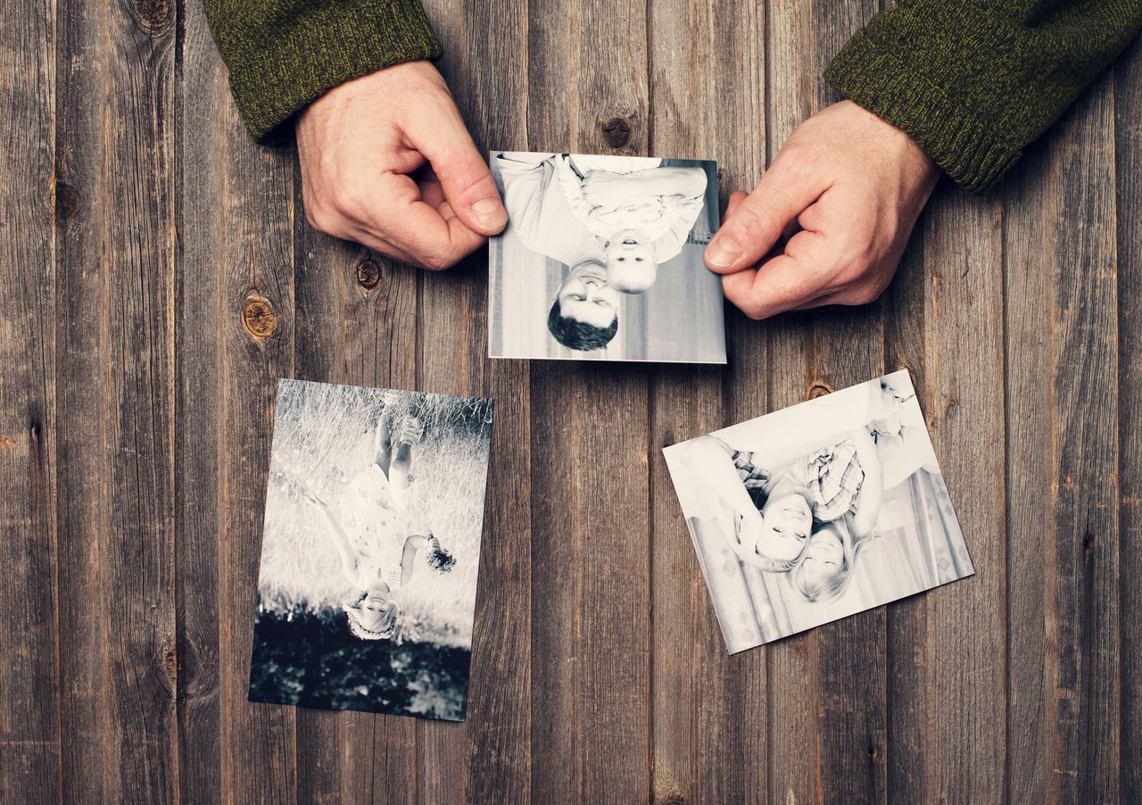 Person looks at old photo of baby and father