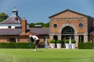 A golfer putts on the putting green at The Grove