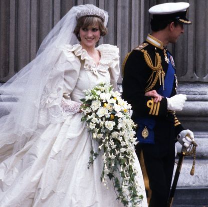 Princess Diana wearing her wedding gown and smiling holding Prince Charles's arm on their wedding day 