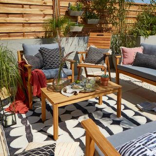 a decked garden with an outdoor rug and a dining table