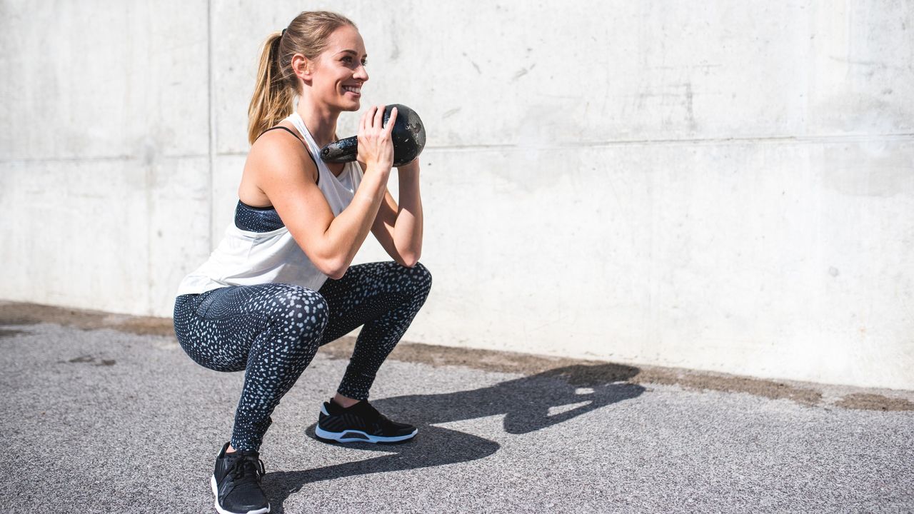 Woman doing a squat with a kettlebell held at her chest