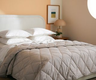 A brown comforter on a bed with white sheets.