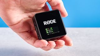 the rode wireless go gen 3 microphone with one receiver, two transmitters, shown against a blue background and with accessories like dead cat, charging ports, and cables