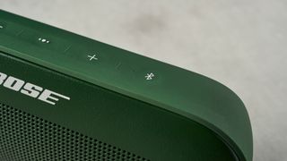 a green bluetooth speaker made by bose with a clean plastic casing and no visible woofers rests on a table