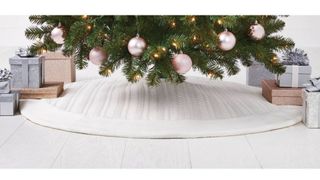 A white cable knit tree skirt under a tree