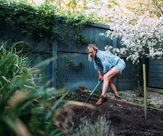 Gardener digging soil to smooth out a garden surface in a small garden