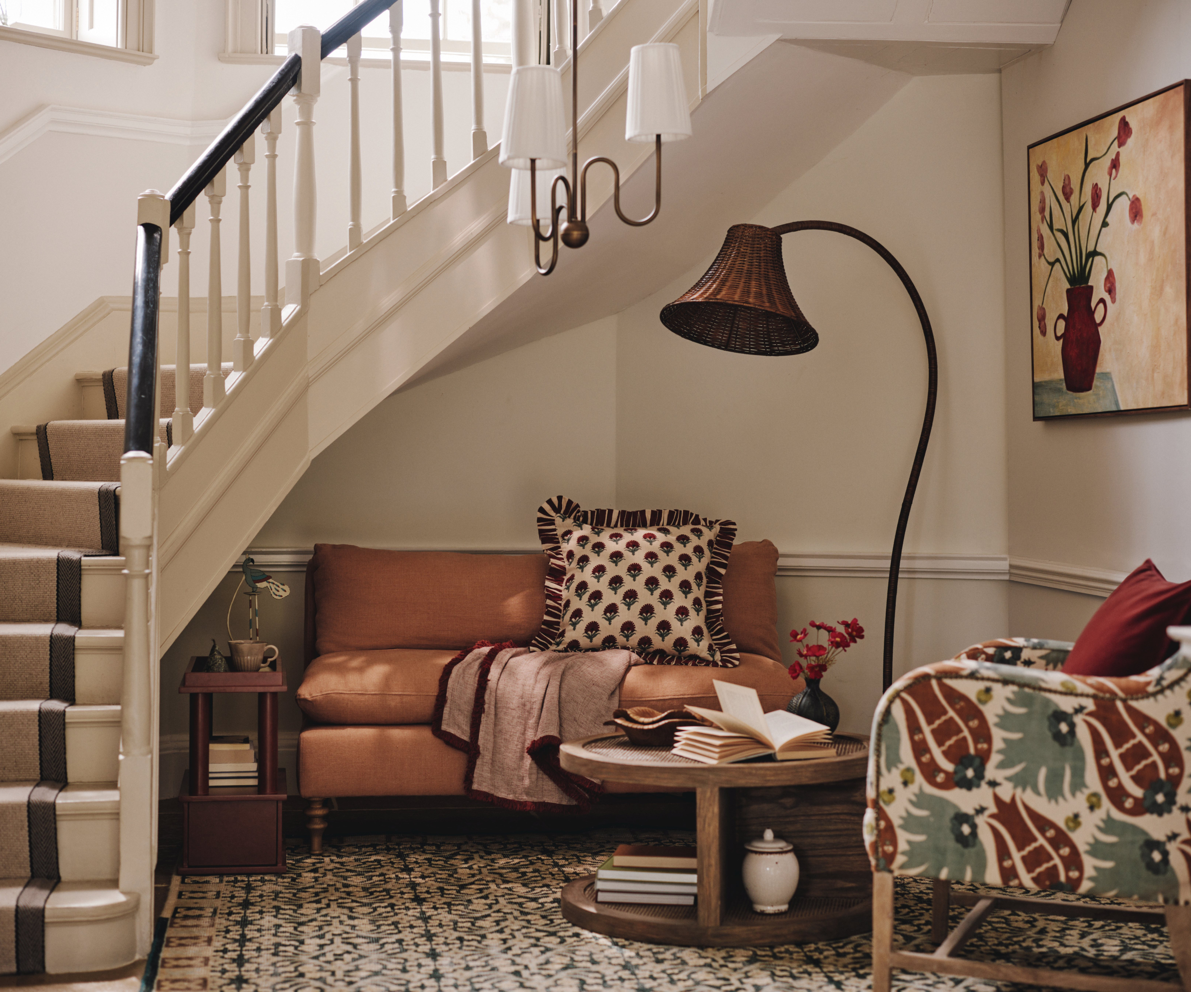 hallway with reading corner with small sofa, chair, pendant light and floor lamp with wicker shade
