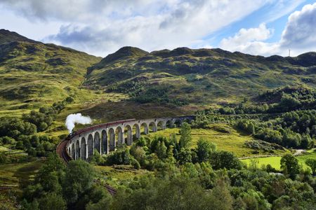 The Glenfinnan Viaduct in Scotland with a steamtrain passing over it