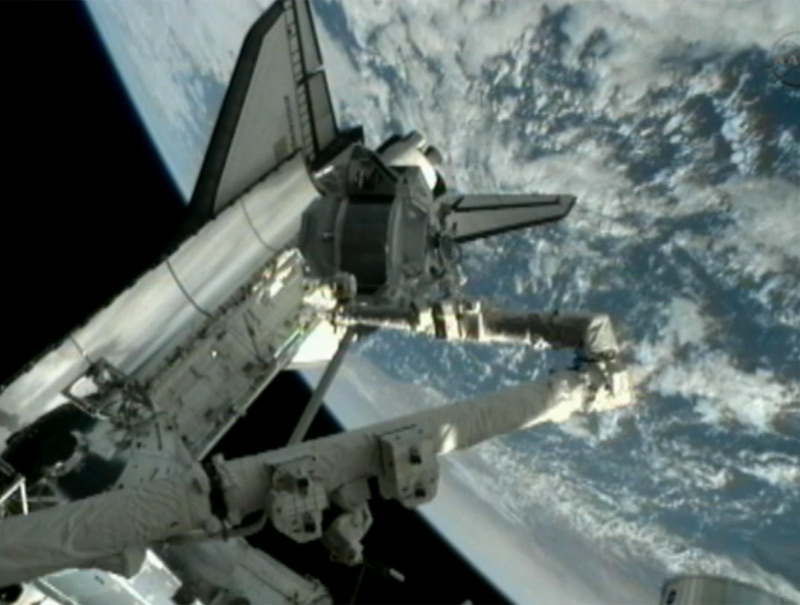 The Alpha Magnetic Spectrometer is transferred out of the space shuttle Endeavour&#039;s cargo bay by the shuttle&#039;s robotic arm on May 19.