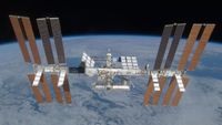 An image of the International Space Station, with its many solar panels and modules, floating above Earth in space