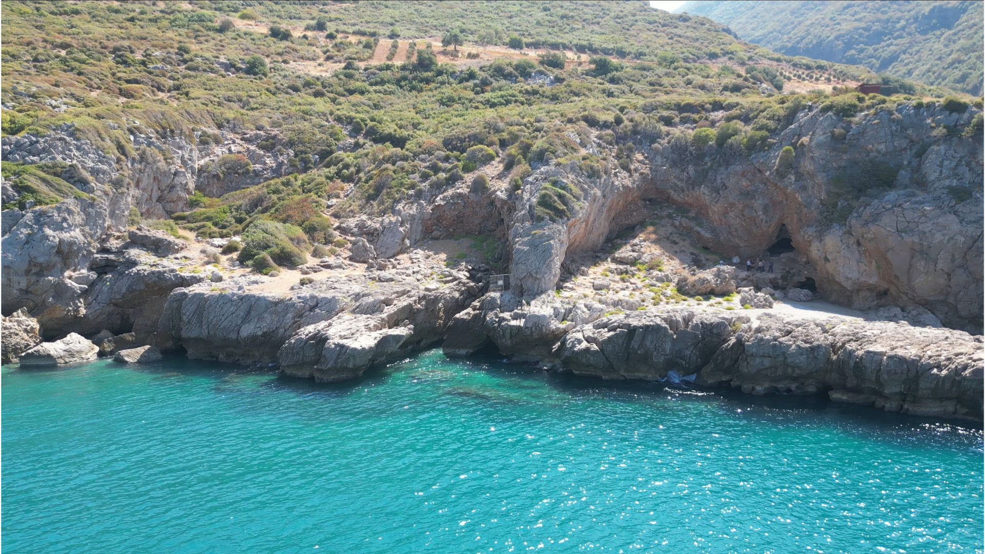 Turquoise waters surrounding rocky entrance to a cave in Turkey.