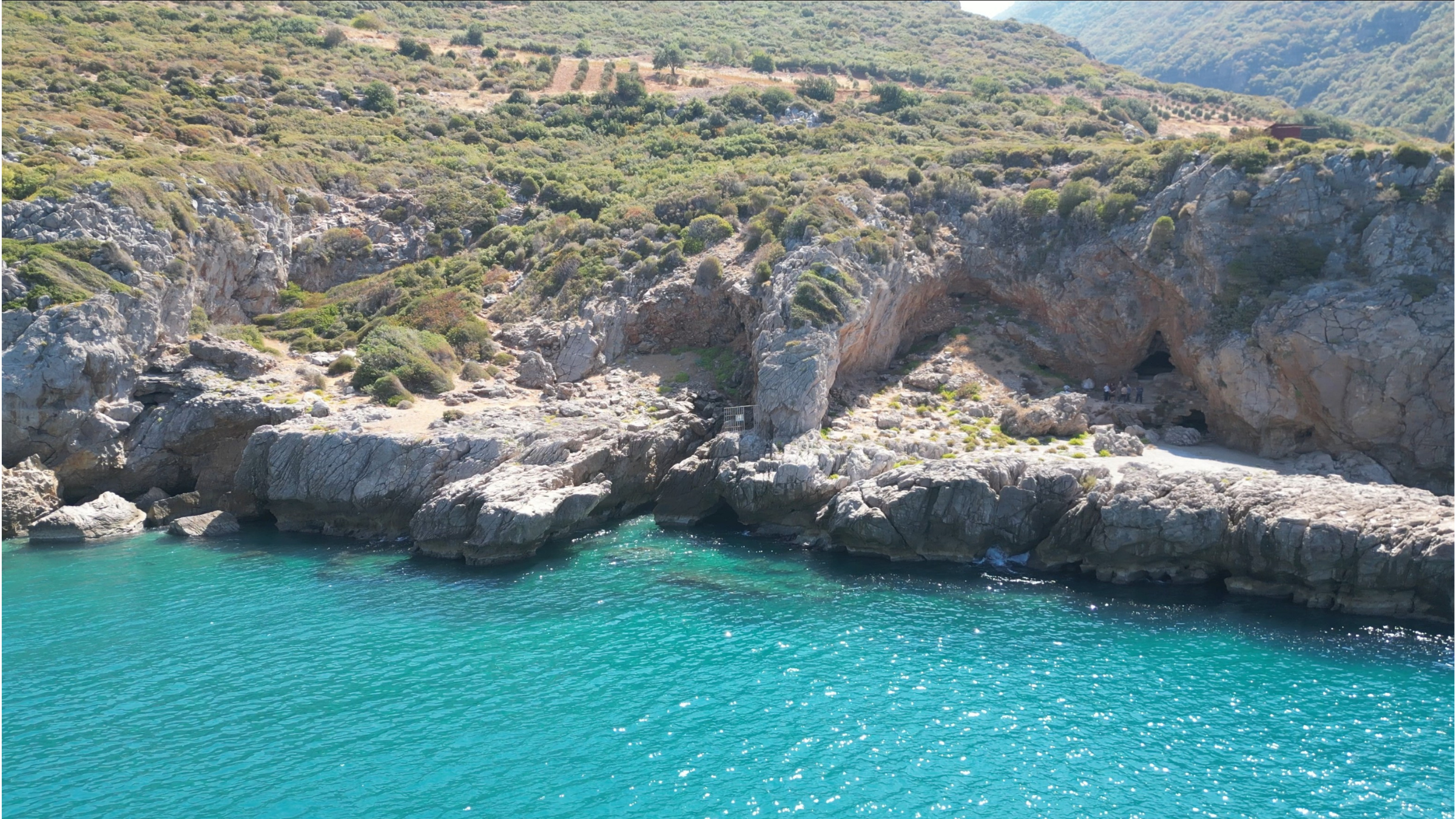 Turquoise waters surrounding rocky entrance to a cave in Turkey.
