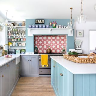 Kitchen with blue island and grey cabinetry and pink patterned tile splashback