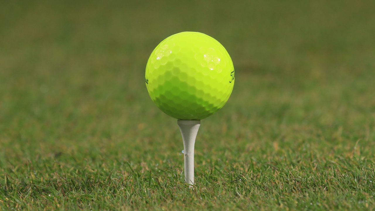 Yellow golf ball pictured on a tee