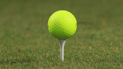 Yellow golf ball pictured on a tee
