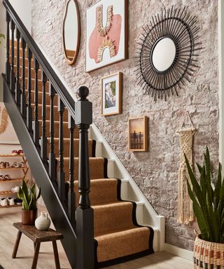A small entryway with a staircase, wall art, mirrors, and a plant