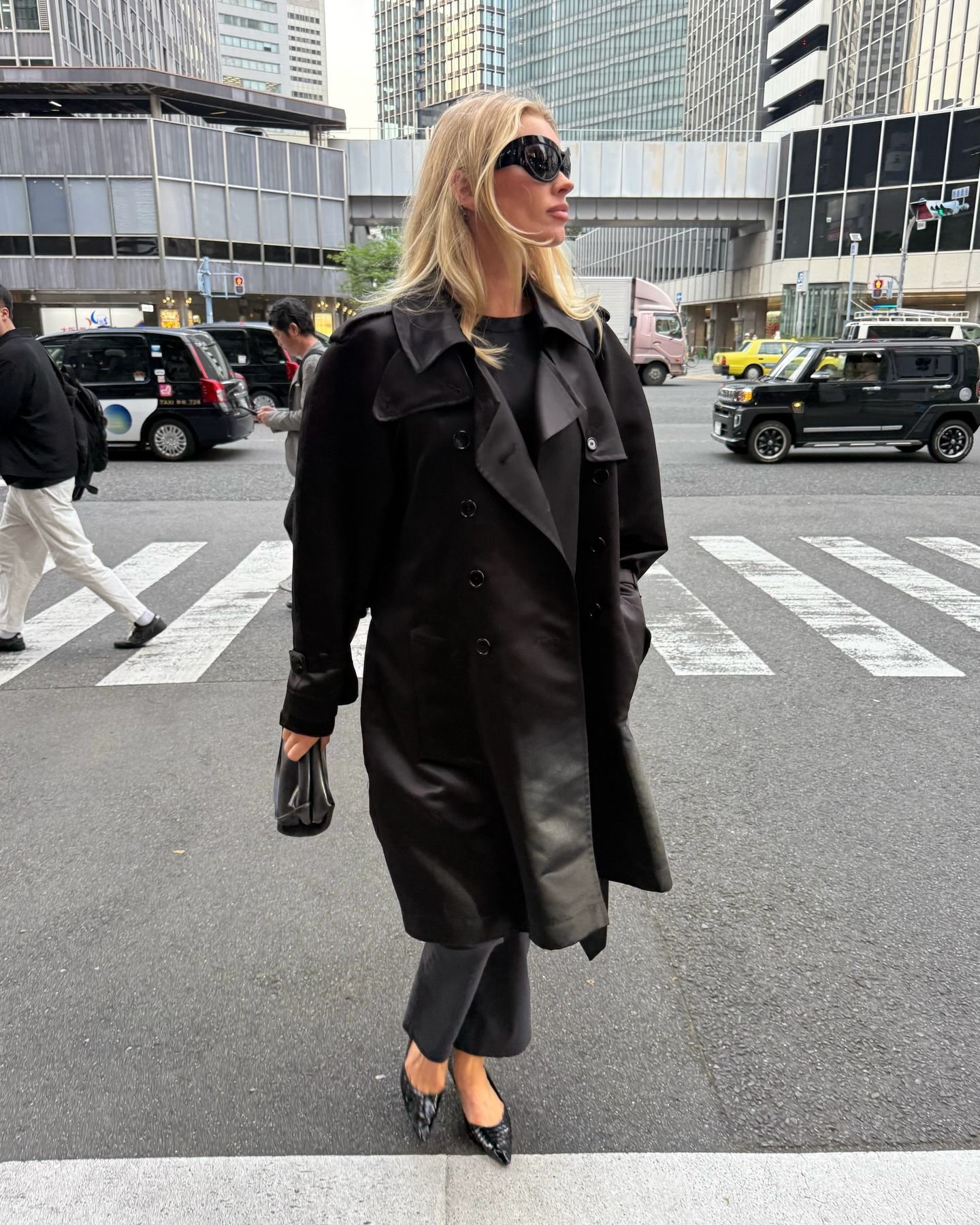 Influencer @hoskelsa wears black cropped trousers with a black trench coat and black pointed-toe shoes.