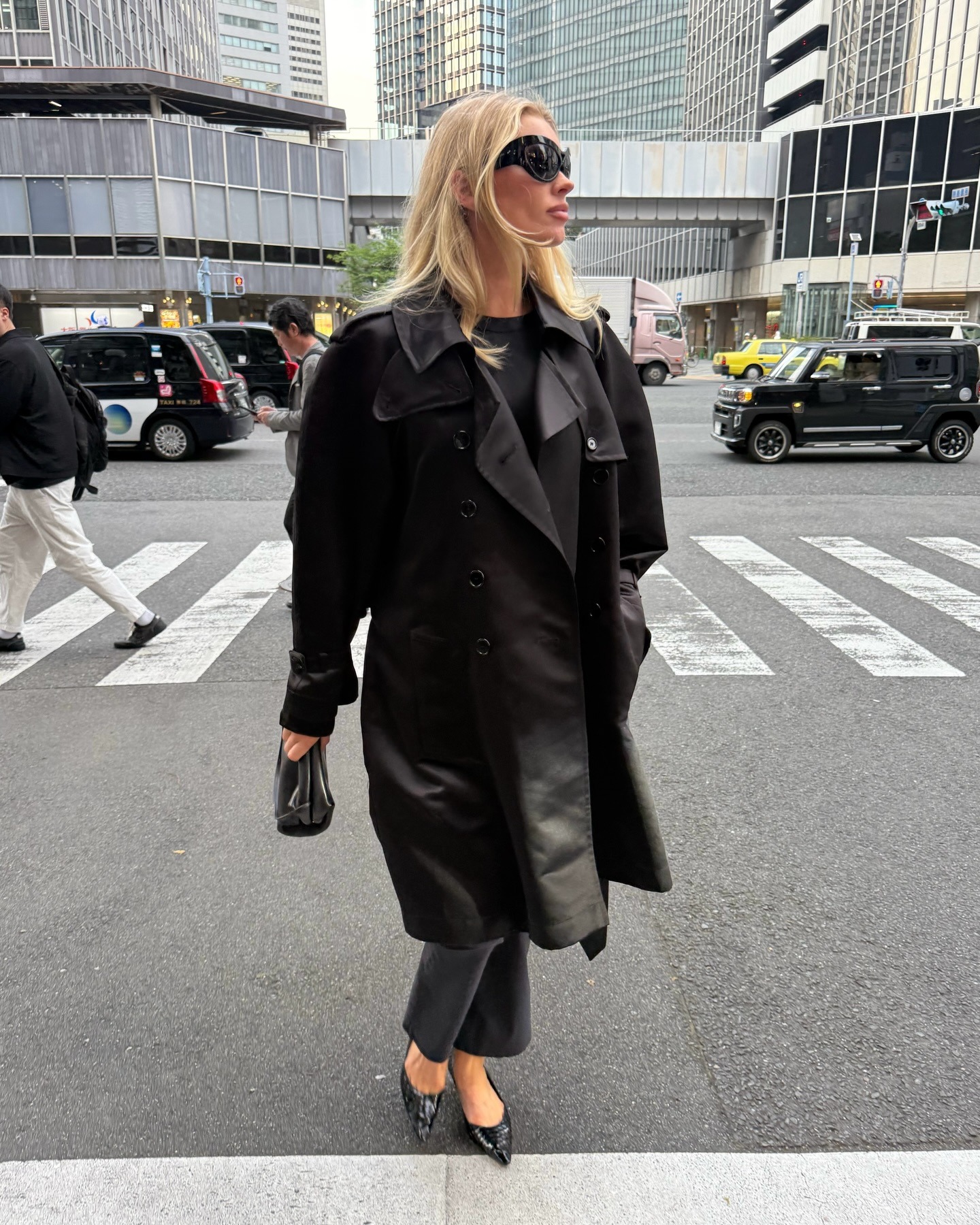 Influencer @hoskelsa wears black cropped trousers with a black trench coat and black pointed-toe shoes.