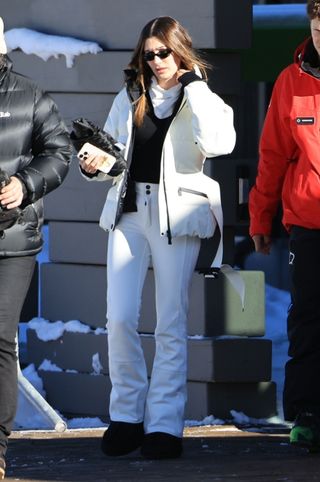 Hailey Bieber wearing a white ski jacket and white snow pants in Aspen.