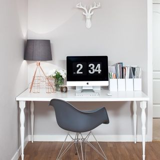 home office with white wall and white desk and grey chair and wooden floor