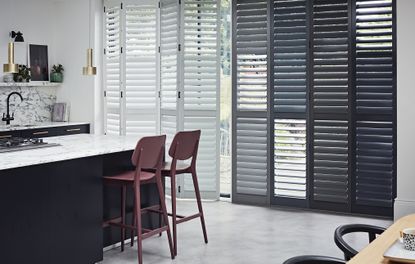 Shutter ideas – kitchen with dark cabinets, pale counters and full length shutters